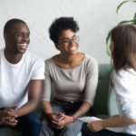 Happy African American couple at successful visit psychologist, smiling wife and husband sitting together on couch after good family therapy session, satisfied clients, help spouses solve problem